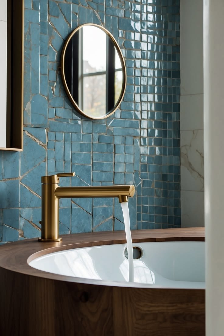 Blue mosaic tile wall with brass faucet over wooden tub